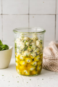 large glass jar with marinated mozzarella balls