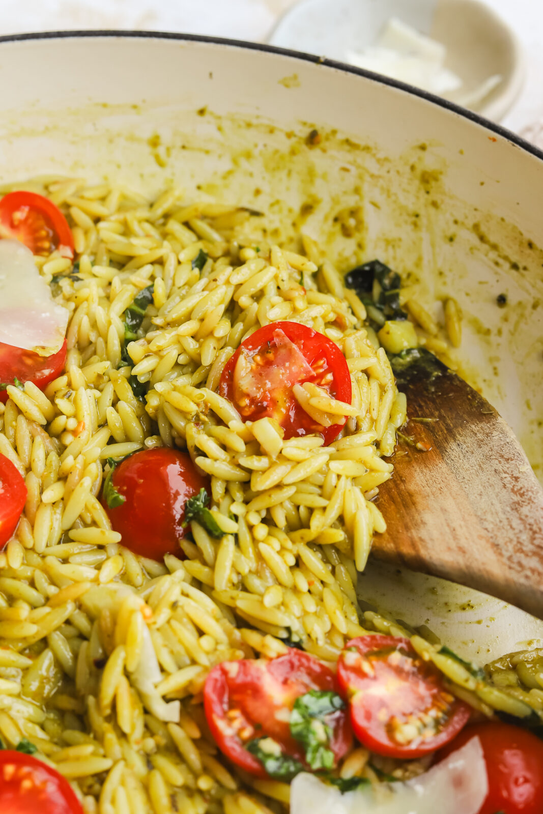wooden spoon scooping up pesto orzo from a pan