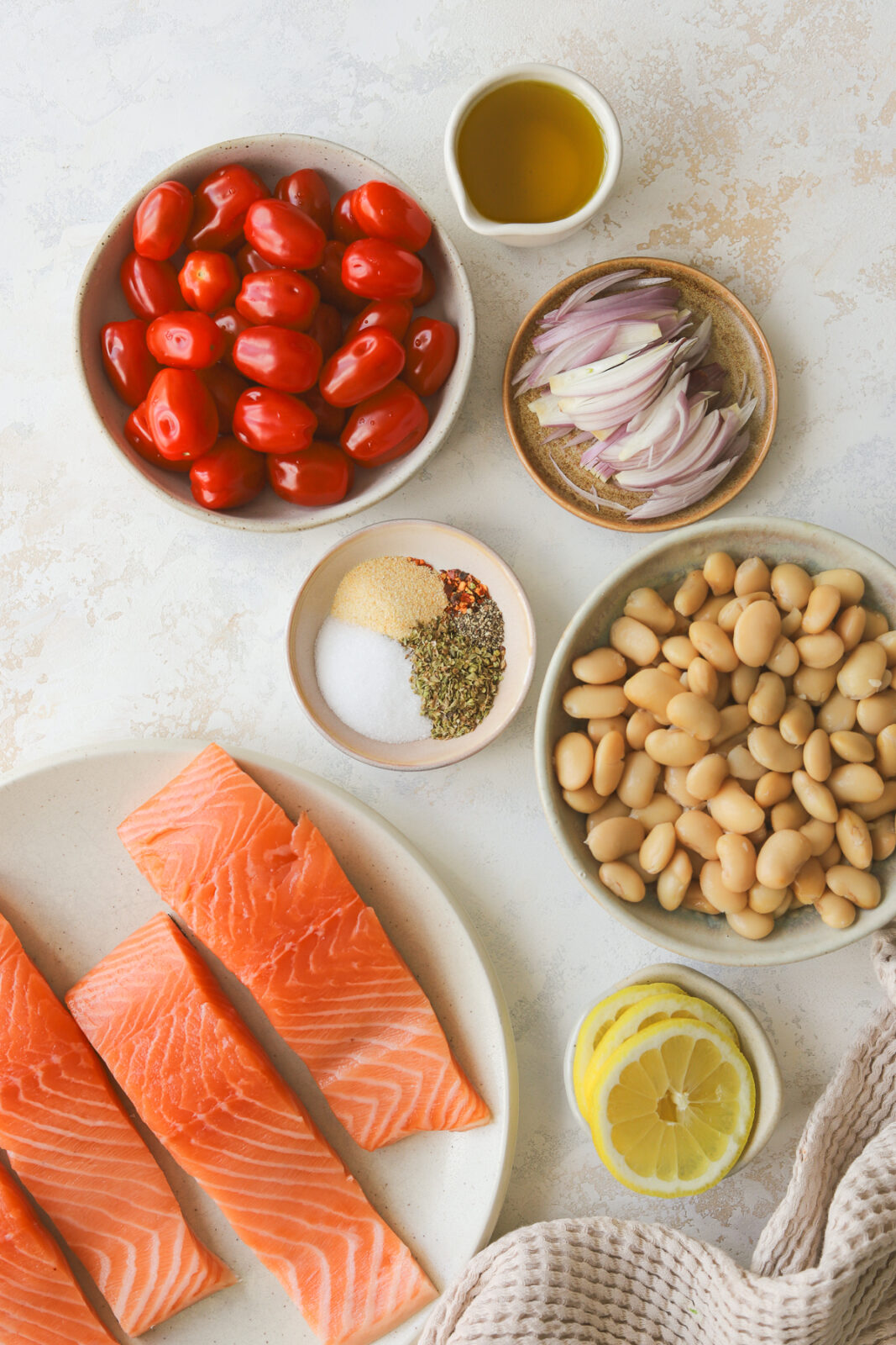 salmon on a plate, beans in a bowl, spices in a small dish and tomatoes in a bowl