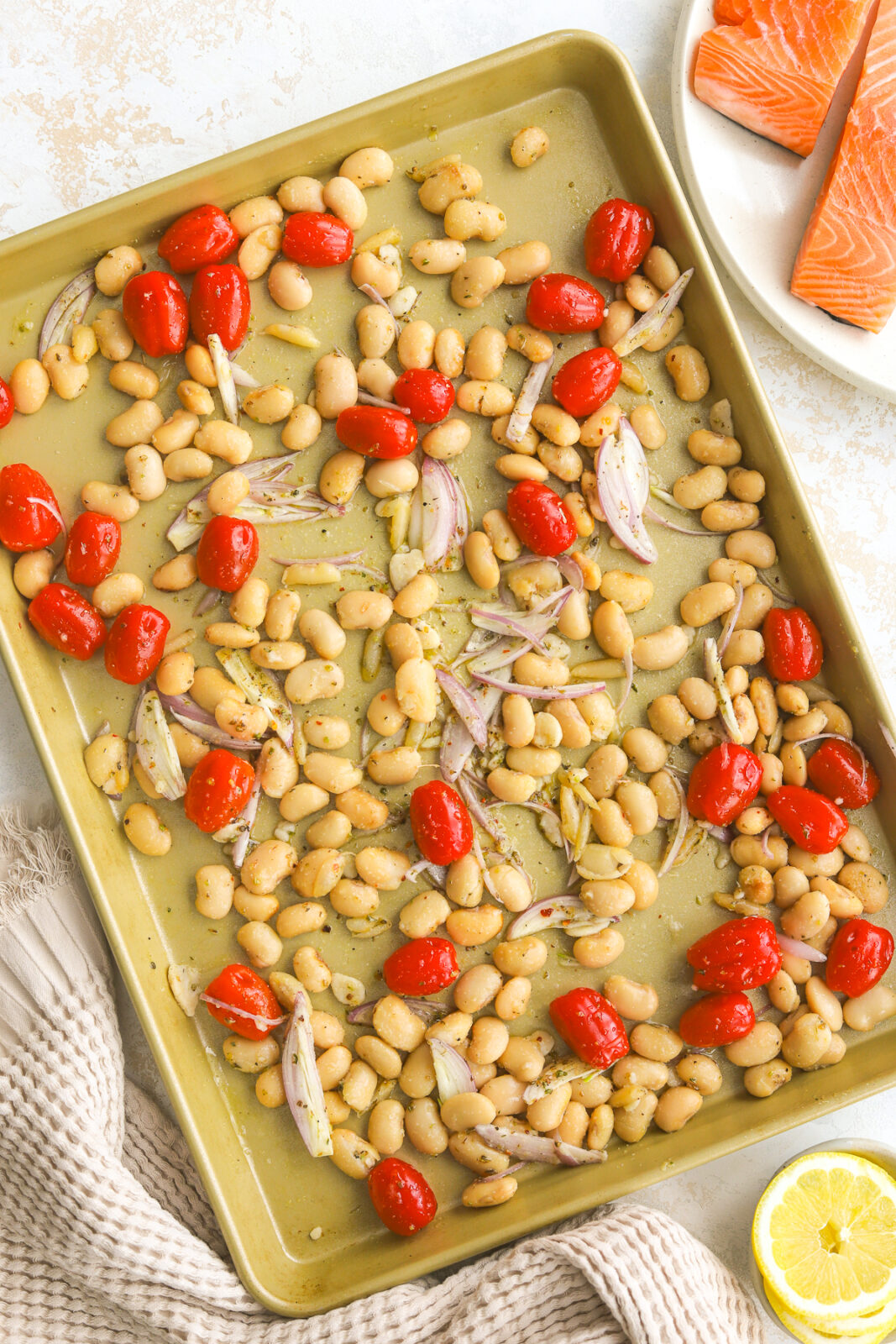 cooked beans and baby tomatoes on a sheet pan with shallots
