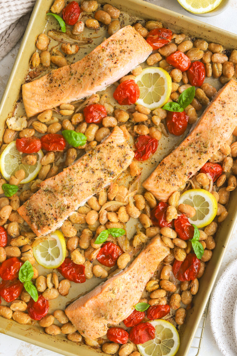 a sheet pan with burst tomatoes, butter beans and salmon fillets