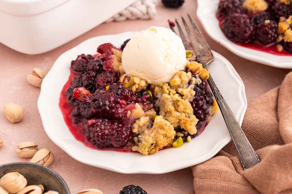 blackberry crumble on a plate with a scoop of ice cream