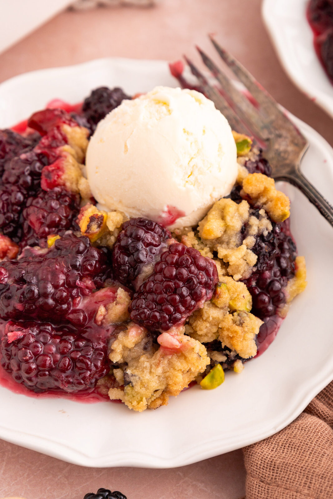 blackberry crumble on a plate with a scoop of ice cream