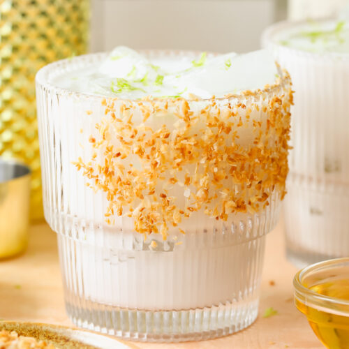 close up of coconut margarita in a glass garnished with toasted coconut