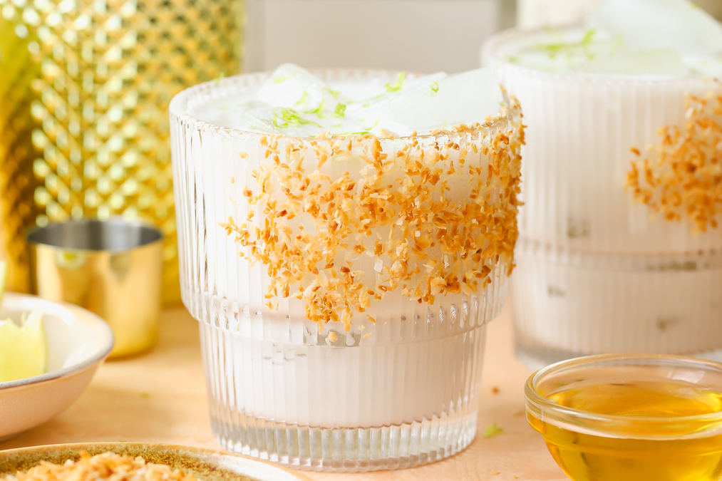 close up of coconut margarita in a glass garnished with toasted coconut