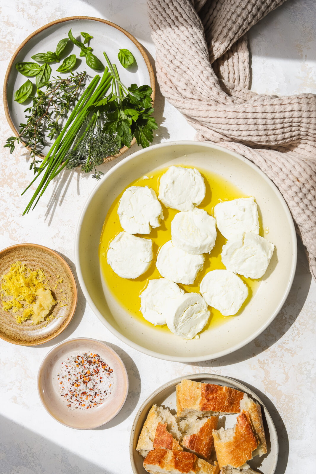 goat cheese, fresh herbs, spices and fresh bread in bowls