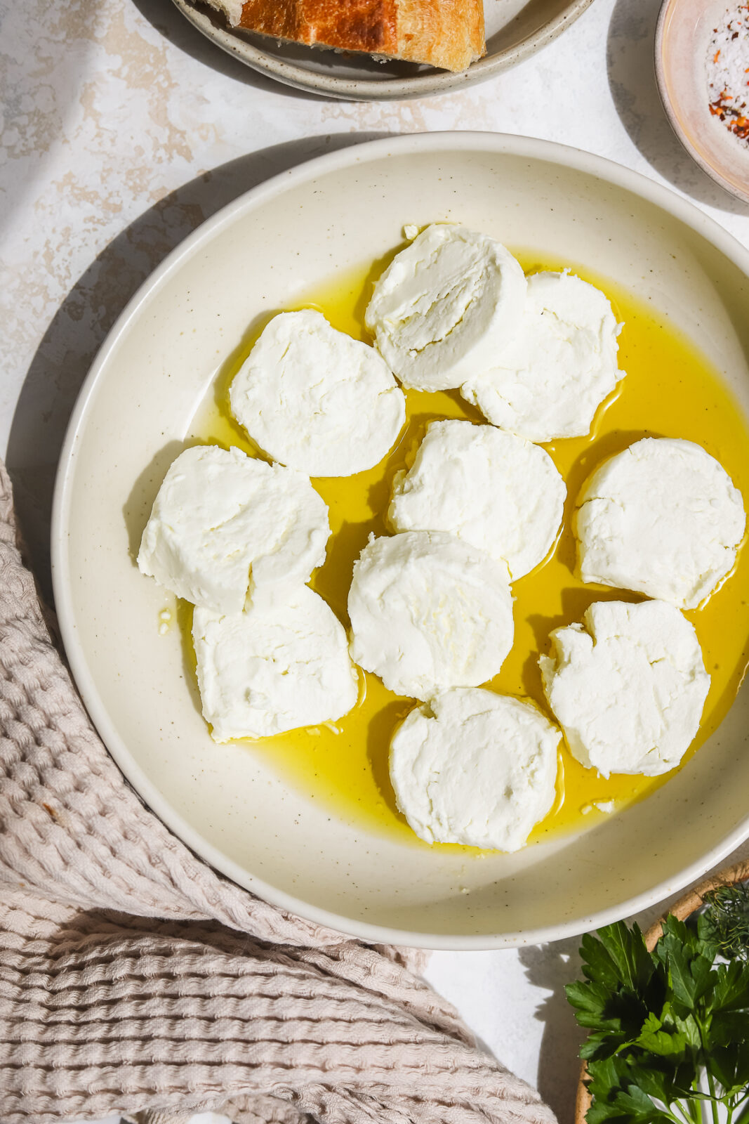 goat cheese rounds with olive oil in a bowl