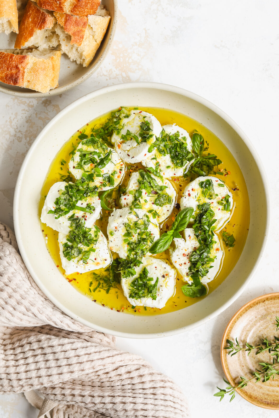 goat cheese marinated with fresh herbs, lemon, olive oil and garlic in a bowl