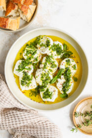 goat cheese marinated with fresh herbs, lemon, olive oil and garlic in a bowl