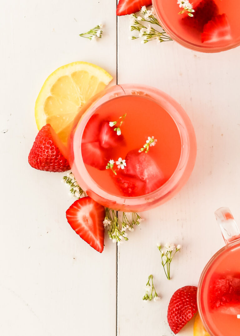 strawberry lemonade cocktail on a serving board with slices of lemons and strawberries