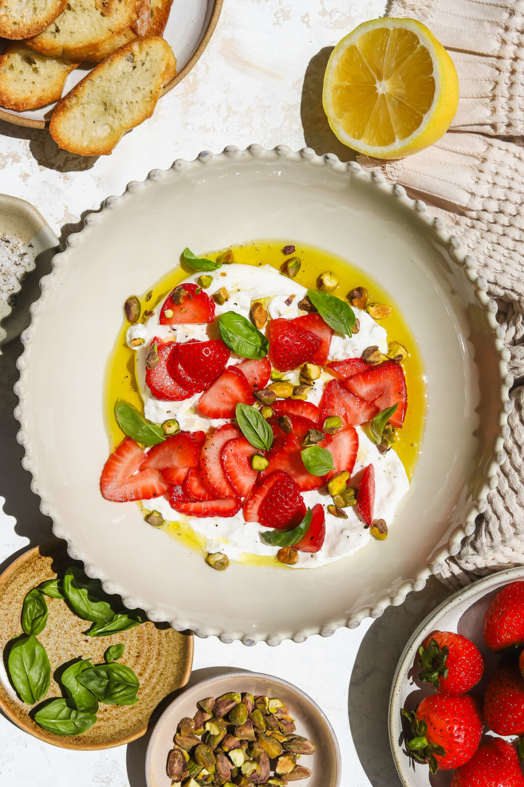 strawberries, burrata, basil, pistachios and olive oil in a bowl