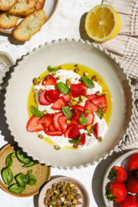 strawberries, burrata, basil, pistachios and olive oil in a bowl