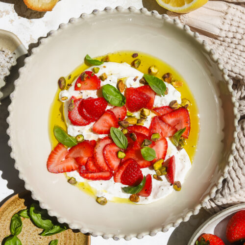 strawberries, burrata, basil, pistachios and olive oil in a bowl