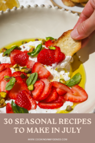 hand holding a crostini dipping it into burrata and fresh strawberries