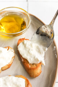 spoon adding burrata to a crostini