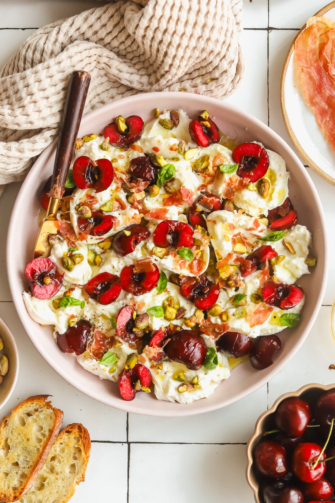 plate of burrata and prosciutto with fresh cherries and basil