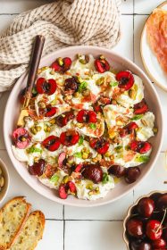 plate of burrata and prosciutto with fresh cherries and basil