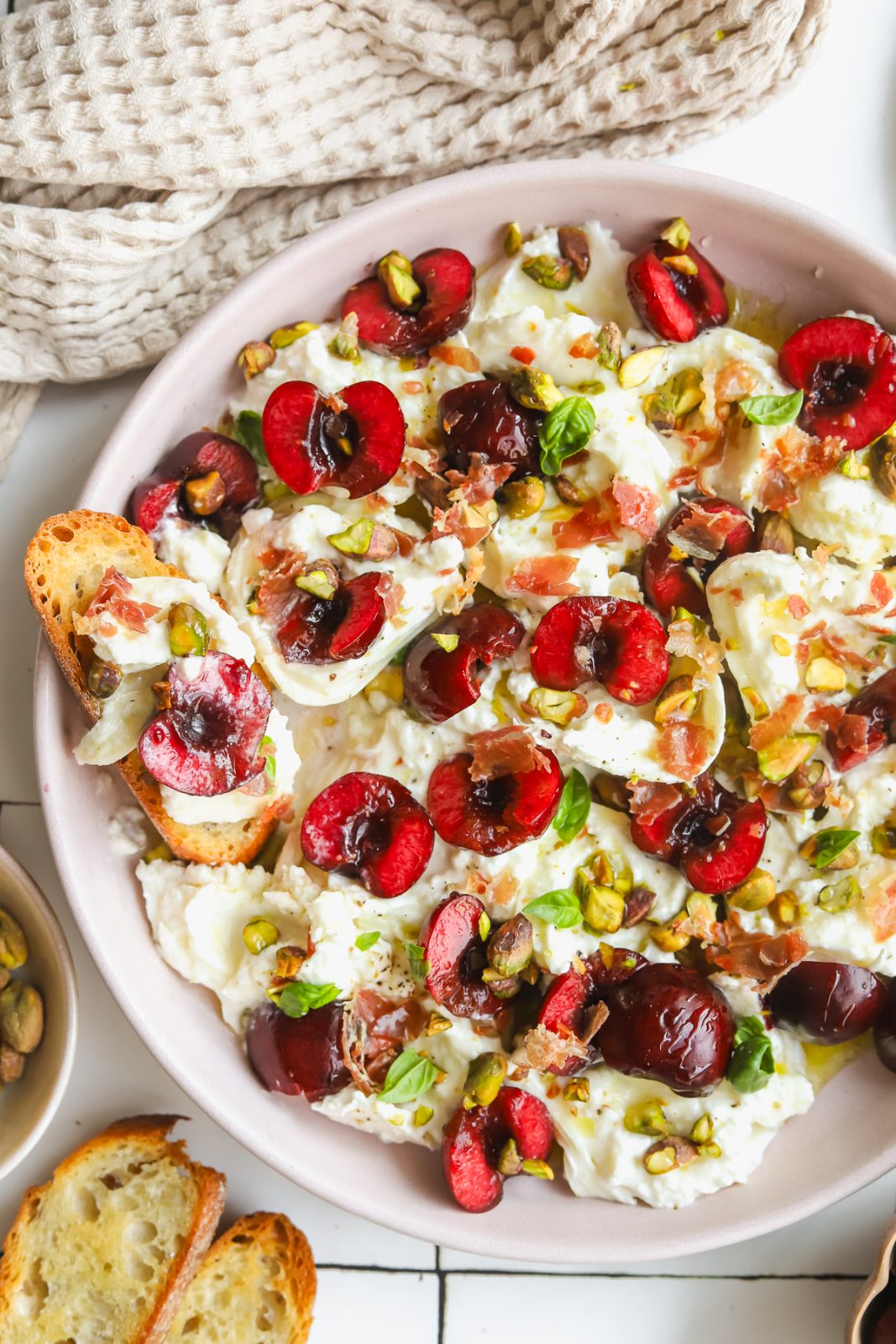 plate of burrata and prosciutto with fresh cherries and basil