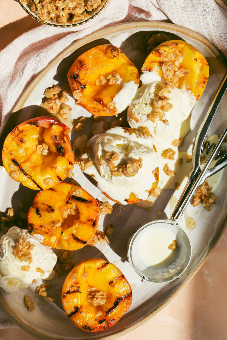 close up of grilled peach halves and scoops of vanilla ice cream on a plate