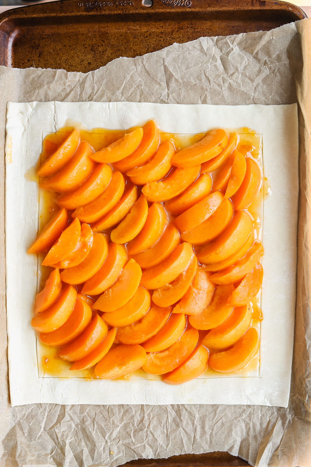 apricot slices lined up diagonally on a piece of puff pastry