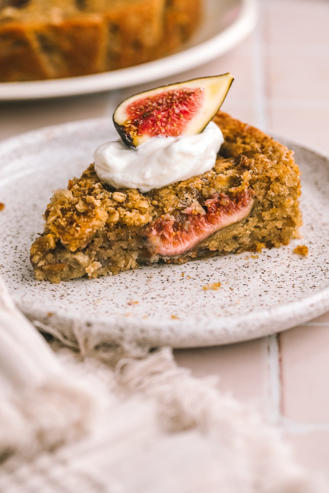 fig cake slice on a plate topped with whipped cream