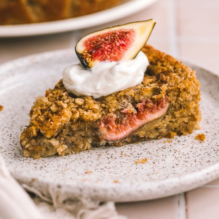 fig cake slice on a plate topped with whipped cream