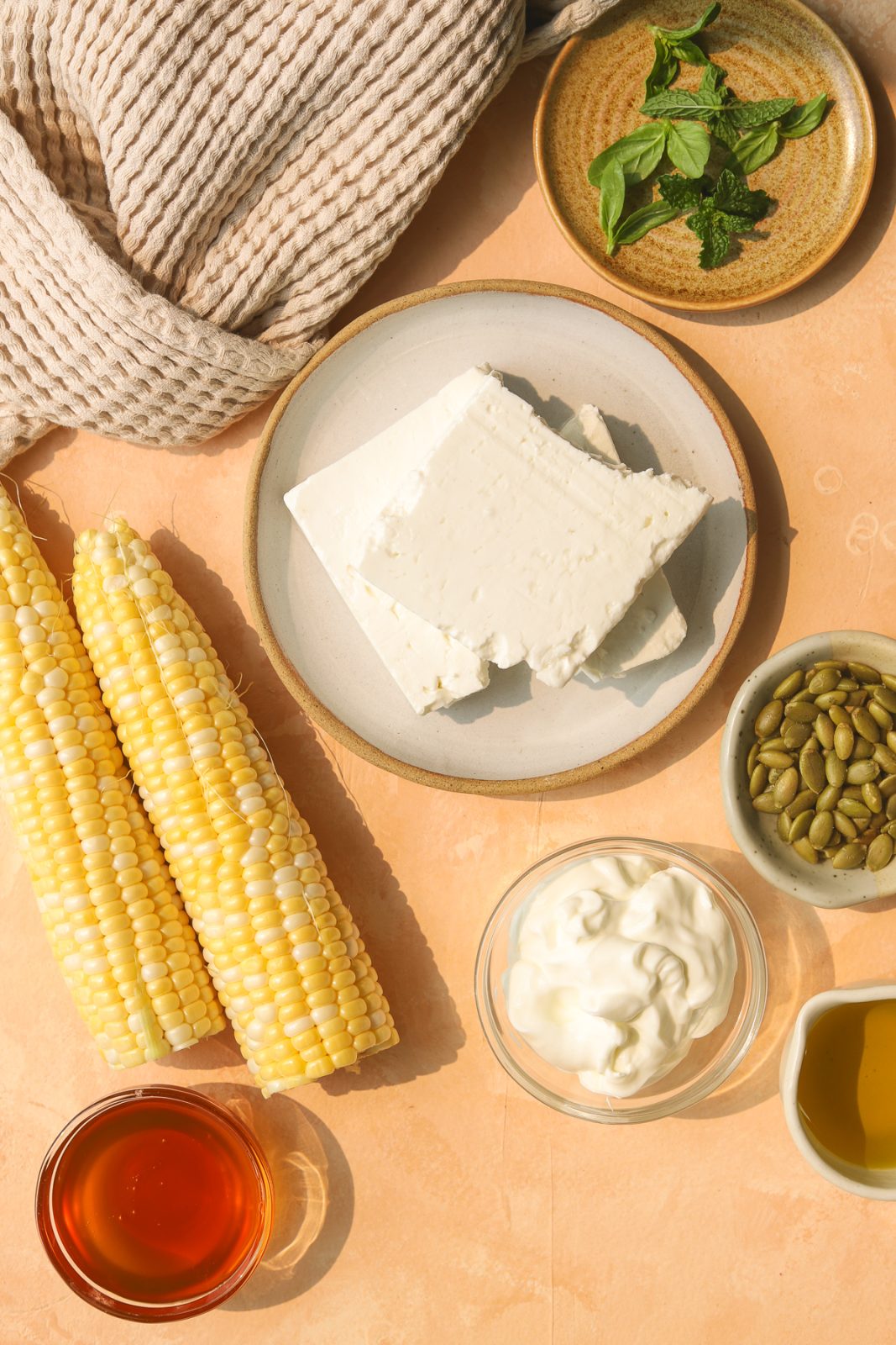 feta on a plate, yogurt in a bowl, hot honey in a bowl, corn on the cob and fresh herbs