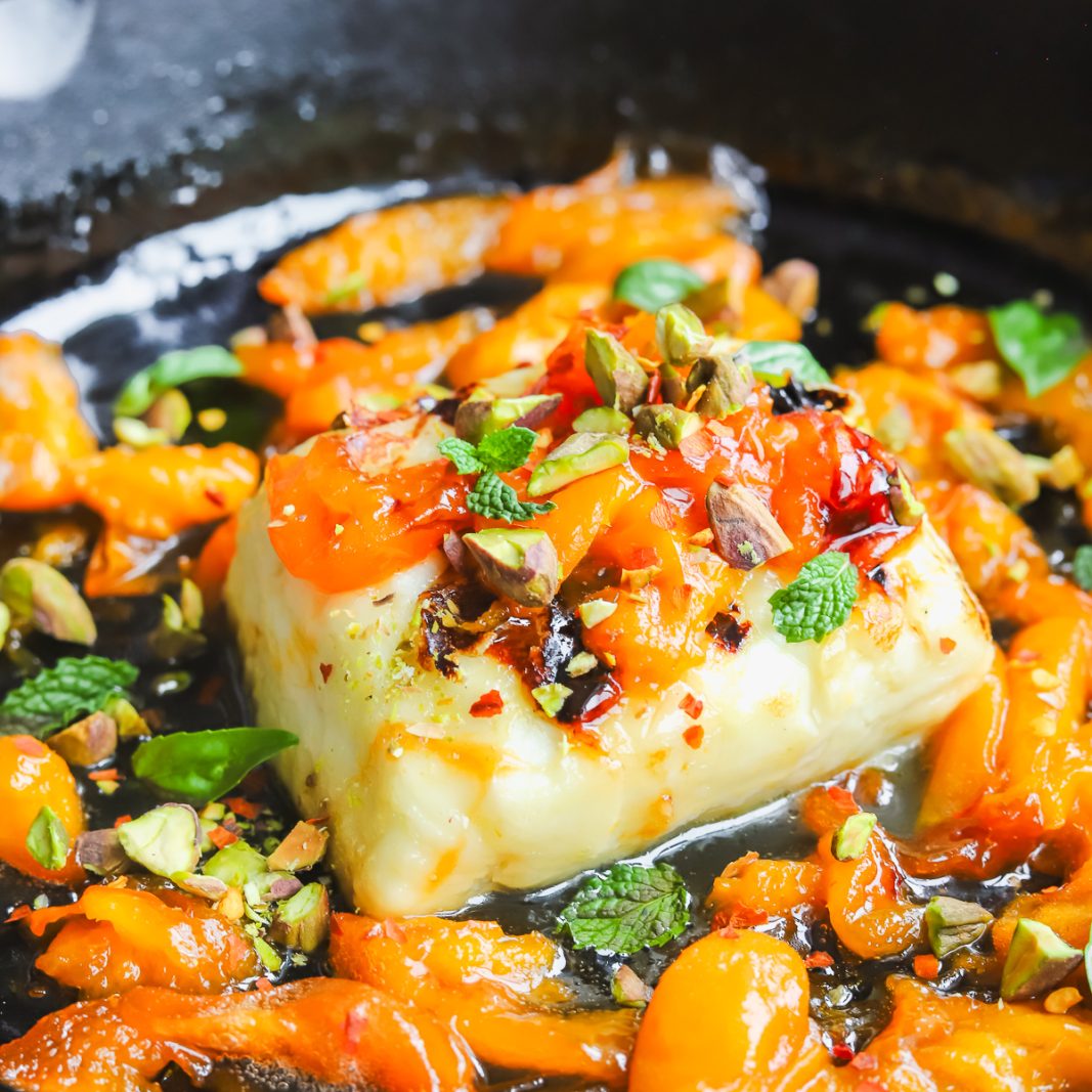 angled photo grilled halloumi with apricot slices in a cast-iron pan