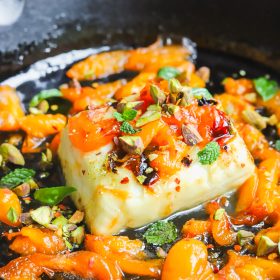 angled photo grilled halloumi with apricot slices in a cast-iron pan