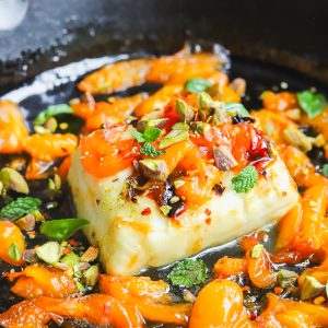 angled photo grilled halloumi with apricot slices in a cast-iron pan
