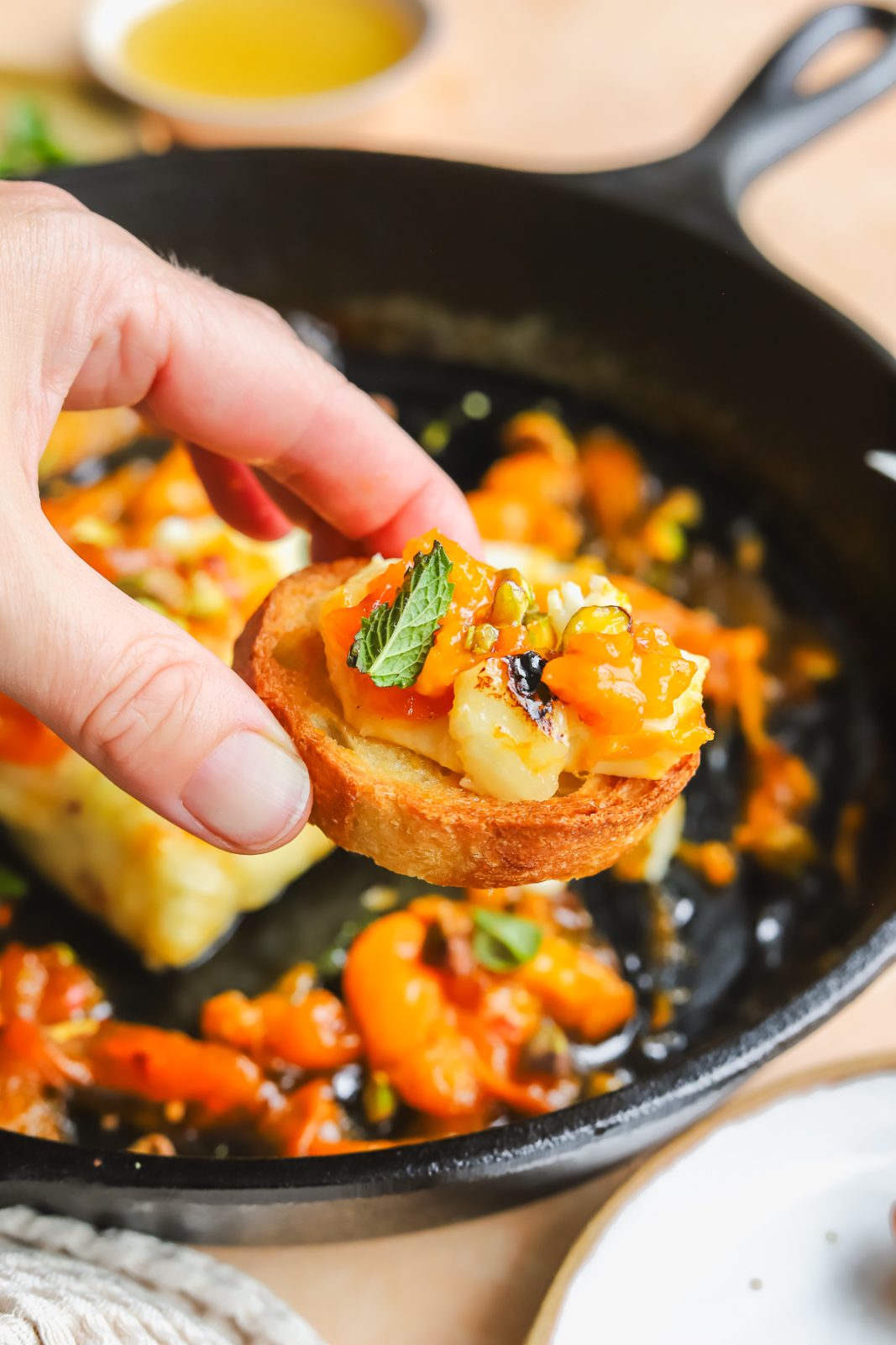 hand holding a crostini with a piece of grilled halloumi and fresh mint