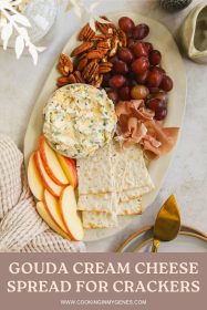 cheese board with cream cheese spread, crackers, apples, pecans, grapes