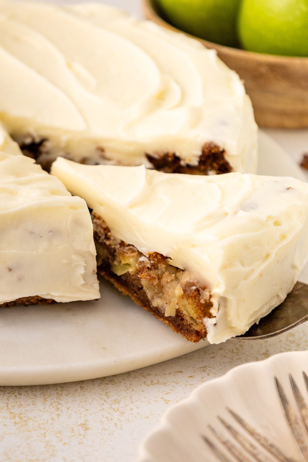 a cut piece of apple cake being pulled out from the cake platter