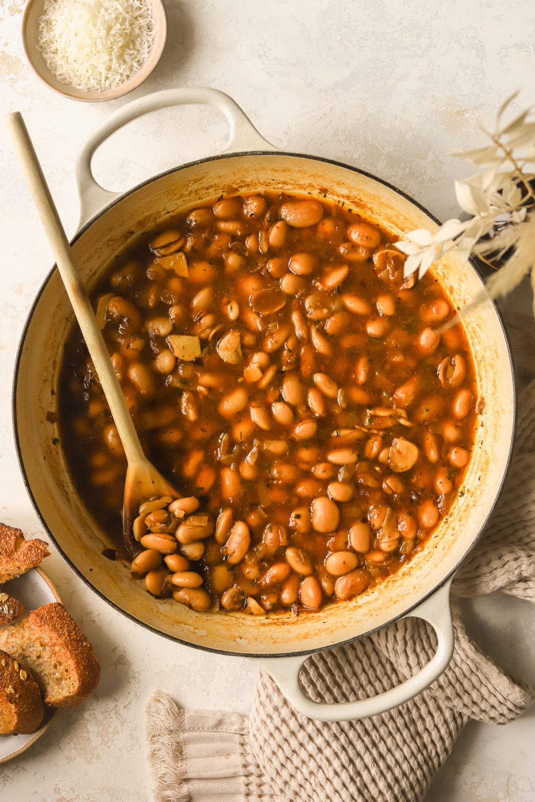 pot with braised white beans, sprigs of fresh thyme and a parmesan rind