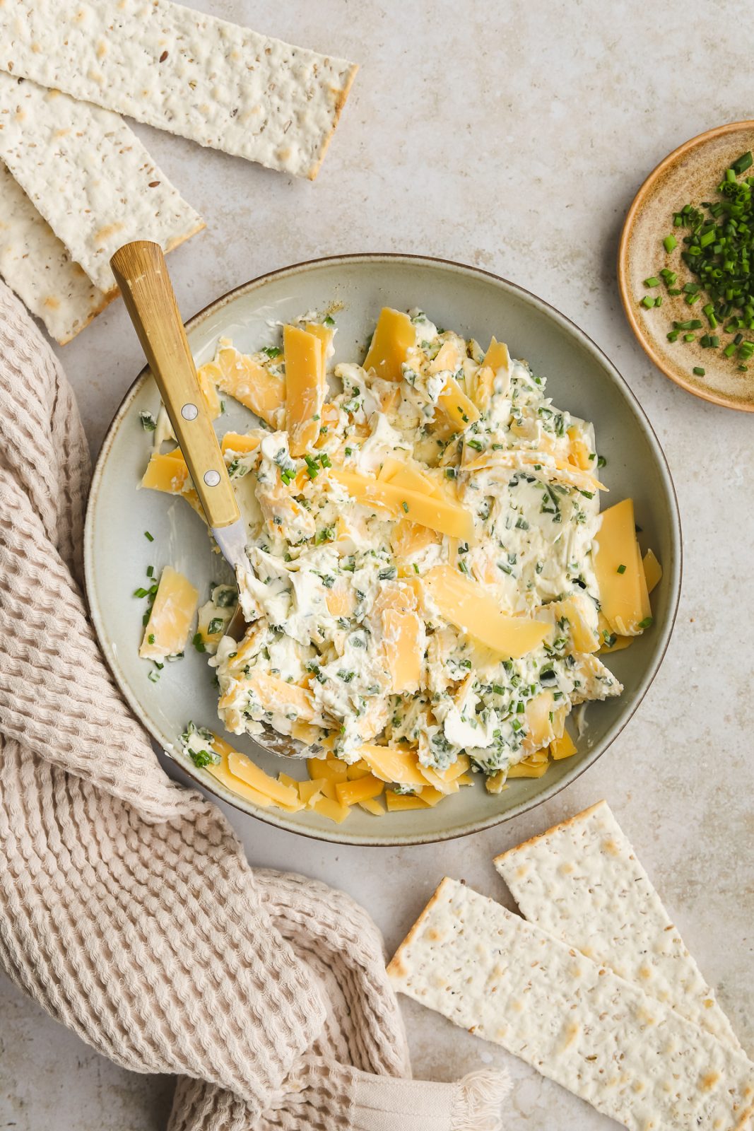 gouda cheese, spices, herbs and cream cheese being mixed in a bowl