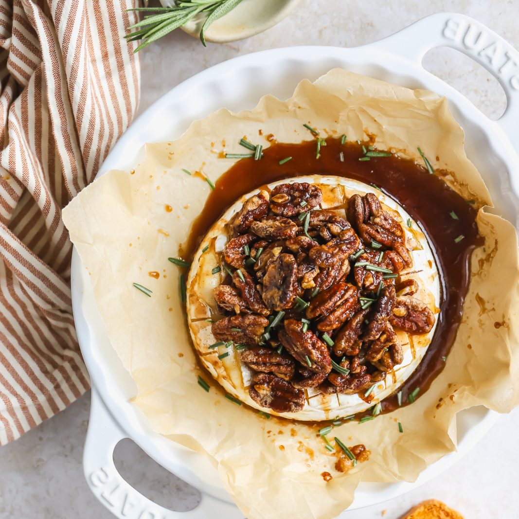 brie cheese in a baking dish with pecans and maple syrup