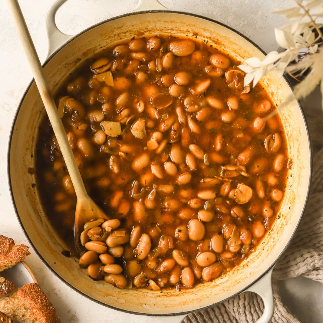 pot with braised white beans, sprigs of fresh thyme and a parmesan rind