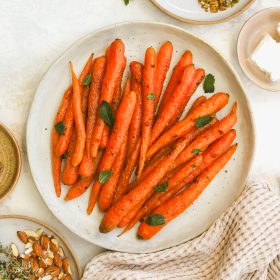 whole roasted carrots on a serving dish garnished with mint