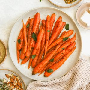 whole roasted carrots on a serving dish garnished with mint