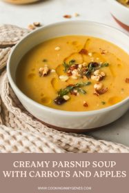 angled photo of a bowl of creamy parsnip soup garnished with olive oil drizzle, chopped hazelnuts and fresh thyme