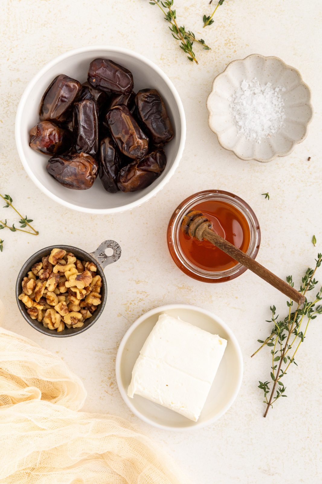 dates in a bowl, honey in a bowl, cream cheese in a bowl, walnuts in a bowl and salt in a dish