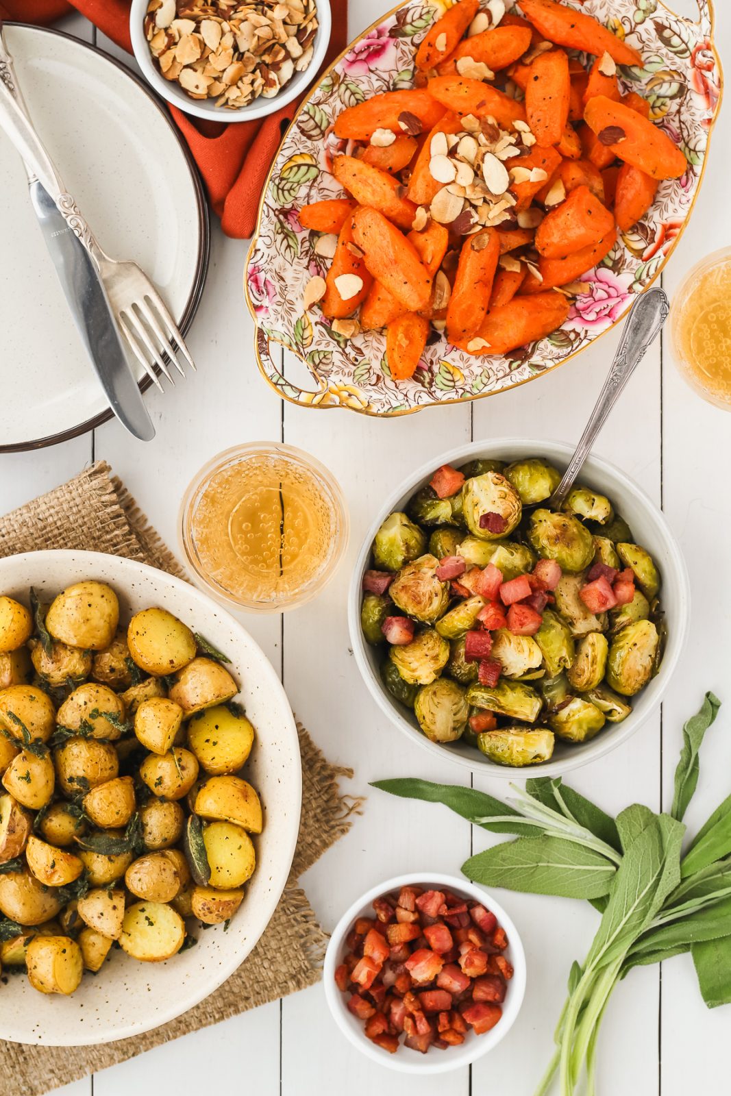 plate of roasted carrots, bowl of roasted potatoes and bowl of roasted brussels sprouts