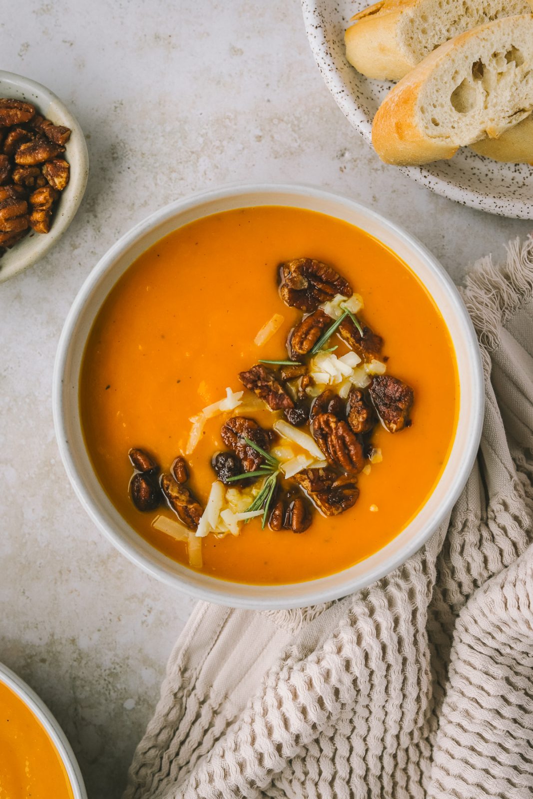 a bowl of sweet potato soup topped with buttery pecans and sharp cheddar cheese