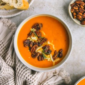 Roasted Sweet Potato & Carrot Soup with Pecan Topping a bowl of sweet potato soup topped with buttery pecans and sharp cheddar cheese